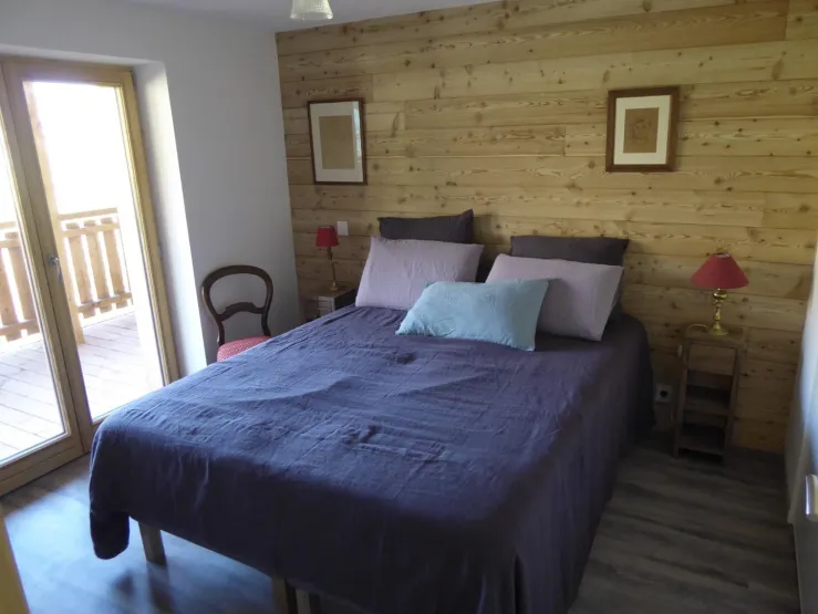 chambre mitoyenne du séjour avec sa porte-fenêtre sur la terrasse et la vue sur les montagnes