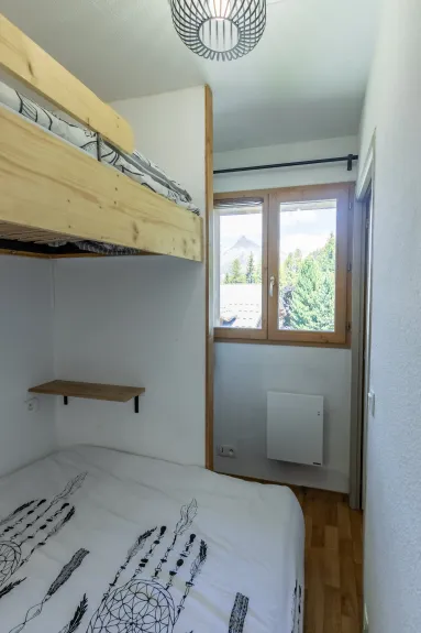 The bedroom has a window with blackout curtains and a radiator