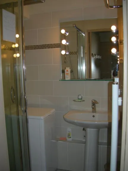 salle de bain carrelée, avec machine à laver ef cabine de douche.