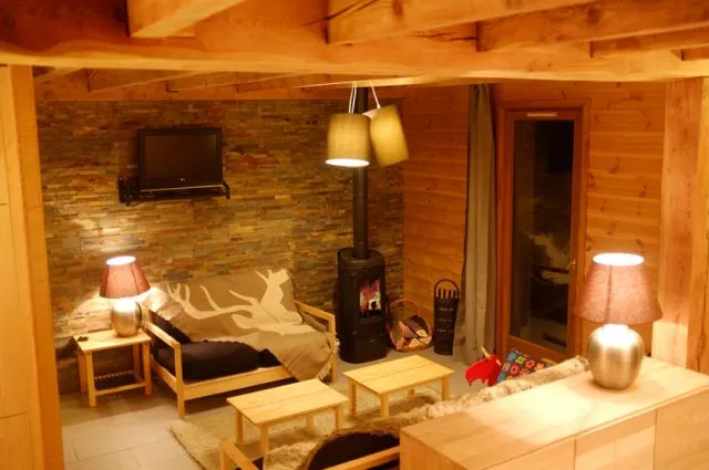 Lounge area designed with exposed beams, stones and wood. Equipped with a wood stove (wood available) and a flat screen TV.