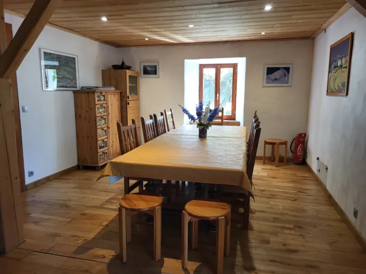 Salle à manger équipée d'une grande table avec 10 chaises et et 2 tabourets.
