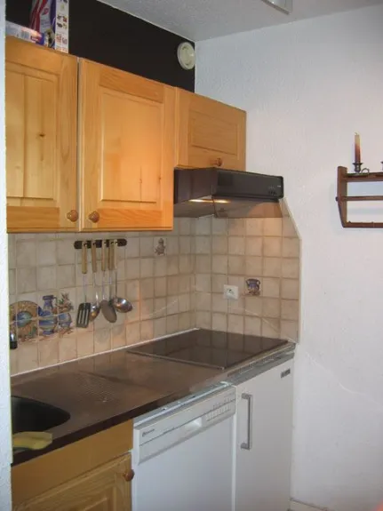 The kitchenette includes a ceramic hob, extractor hood, sink, refrigerator, dishwasher, and cupboards.