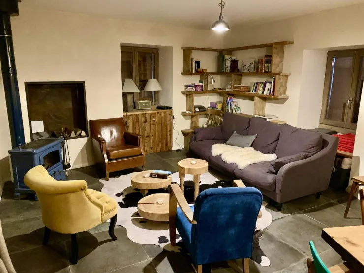 Living room with wood stove, tv, game console, board games, library, sofa, armchairs, coffee tables.