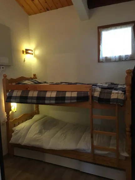 Dans l'entrée, séparée du séjour par une porte, un lit superposé avec 3 coffres de rangements de vêtements