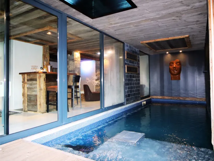 Piscine intérieure chauffée à 28°C au Chalet D à Vars, offrant une vue directe sur le bar privé de l'espace détente