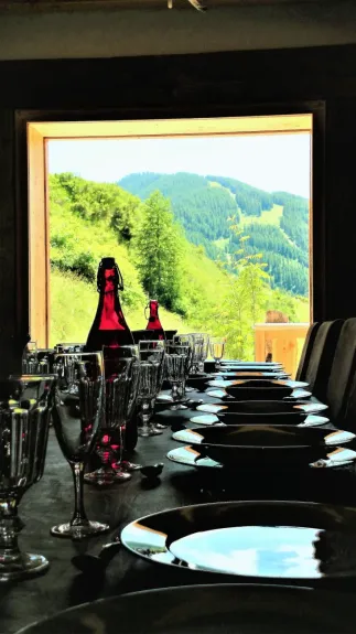 Repas montagnard  : table de salle à manger pour 19 convives prête pour une raclette face au panorama de la montagne


