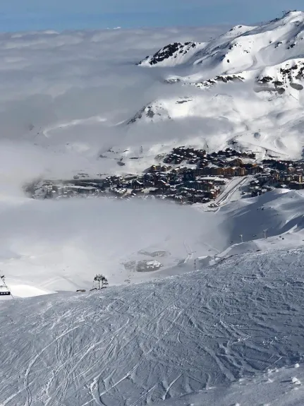  Depuis une piste de ski  , vue du village de Val Thorens perdu dans les nuages par un jour de beau temps .
