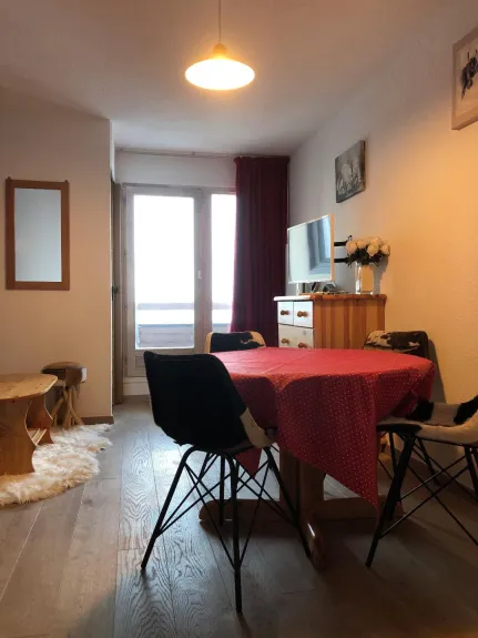 Séjour avec table ronde et chaises , vue par la porte fenêtre sur les pistes de ski