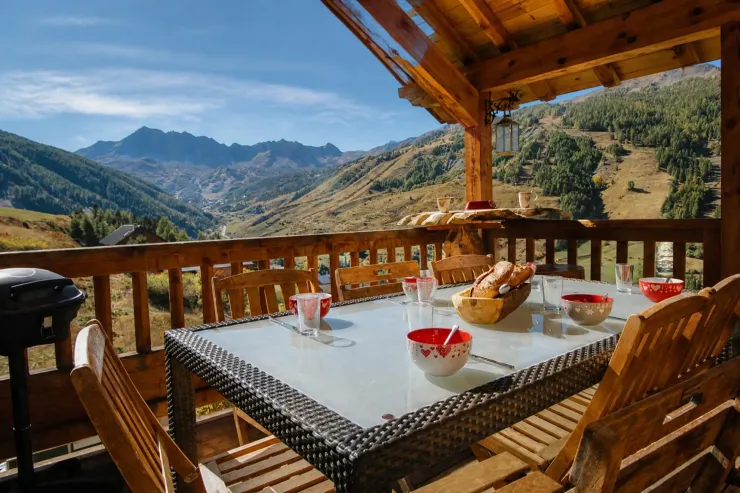 Terrace du Chalet C à Vars lors d'une matinée d'automne, avec une table dressée pour le petit-déjeuner et une vue panoramique sur la crête de l'Eyssina.
